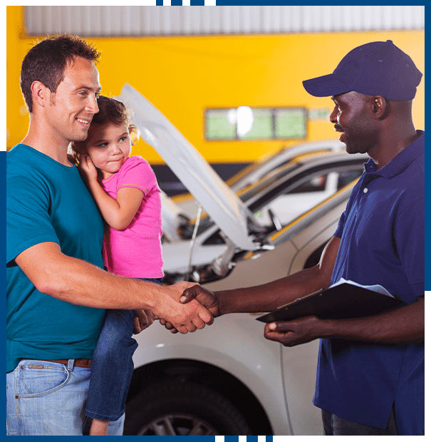 friendly auto mechanic handshaking with family inside workshop